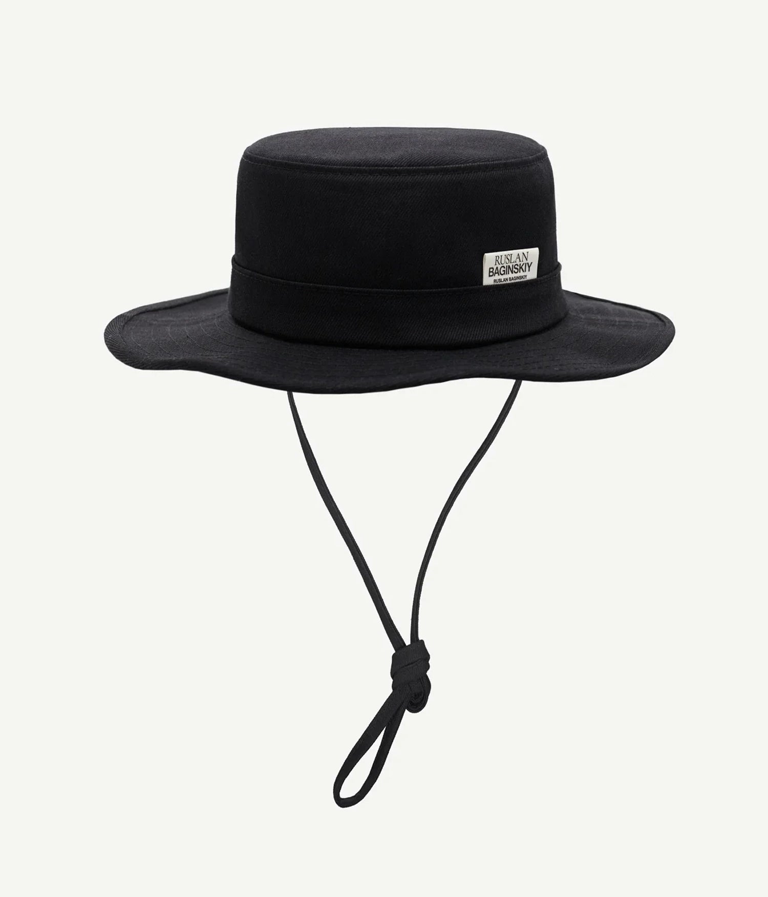 44_10, Ruslan Baginskiy Black Bucket Hat with TiesCrafted from dense black denim, this bucket hat features structured panels and neatly topstitched brims. The clean shape is accented with a branded logo patch on the crown and long ties for comfortable wear. The sturdy material extends the seasonality of the piece.Handcrafted in Ukraine.