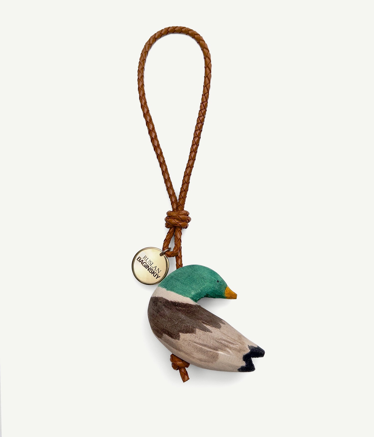 ALLwithoudDIS, RB Bag Charms embody deeply familiar symbols, each carries the emotional legacy of home. Each with its own character — a traveler or a guardian, a dreamer or a quiet observer. Hand-carved from natural wood, delicately painted each bag charm features a leather strap, and finished with an RB metal logo-medallion.The Ducks — finding peace along calm riverbanks, they symbolize inner calm and serenity. Ducks invite us to pause, to listen, and to reconnect with the stillness of nature.